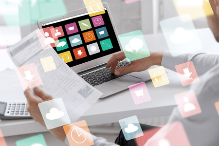 business, technology, multimedia and people concept - businessman with menu icons on laptop computer screen working at officeの写真素材