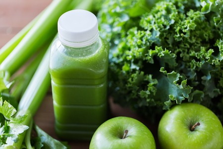 healthy eating, food, dieting and vegetarian concept - bottle with green juice, fruits and vegetables on wooden tableの写真素材
