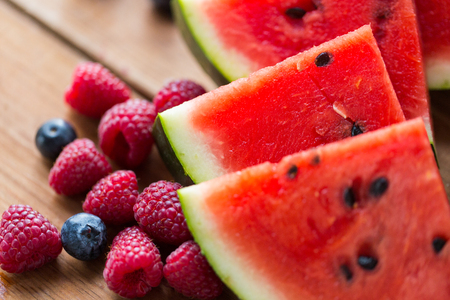 healthy eating, food, dieting and vegetarian concept - close up of raspberry, blueberry and watermelon slices on wooden tableの写真素材