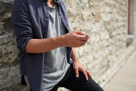 leisure, technology, communication and people concept - close up of man with smartphone at stone...