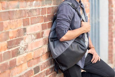 travel, tourism, lifestyle and people concept - close up of man with backpack standing at city street wallの写真素材