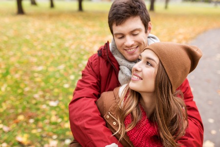 love, relationships, season and people concept - happy young couple hugging in autumn parkの写真素材
