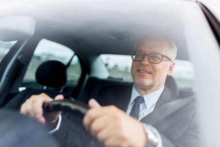 transport, business trip and people concept - happy senior businessman driving carの写真素材