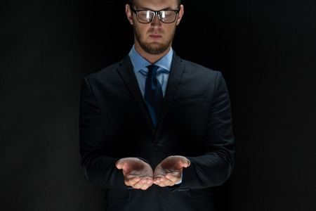 business, virtual reality, people and advertisement concept  - close up of businessman in suit holding something imaginary on palms of his handsの写真素材