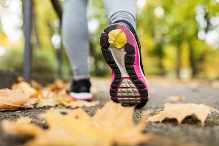 fitness, sport, people, wear and healthy lifestyle concept - close up of young woman running in autumn parkの写真素材