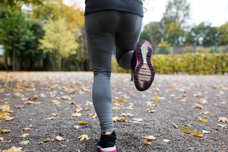 fitness, sport, people, wear and healthy lifestyle concept - close up of young woman running in autumn parkの写真素材