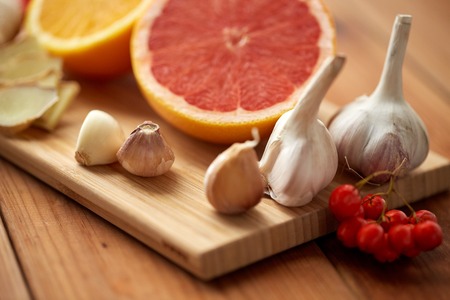 traditional medicine, cooking and ethnoscience concept - orange, grapefruit with ginger and garlic on wooden boardの写真素材