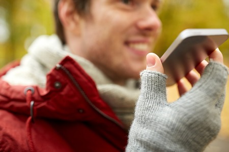 leisure, technology, communication and people concept - close up of smiling hipster man using voice...