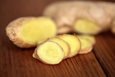 ethno science, culinary, diet, eco food and objects concept - close up of ginger root on wooden...