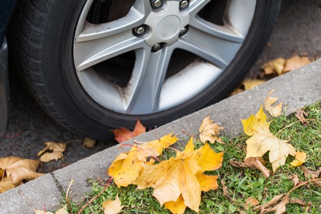 season and transport concept - close up of car wheel and autumn leavesの写真素材