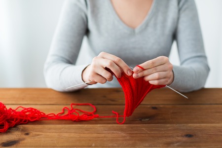 people and needlework concept - woman hands knitting with needles and red yarnの写真素材