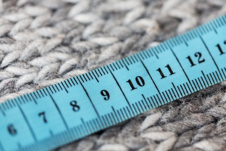 handicraft, knitwear and needlework concept - close up of knitted item with measuring tapeの写真素材