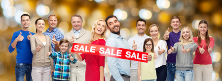shopping, family, generation and people concept - group of happy men and women showing thumbs up and sale sign over holidays lights backgroundの写真素材