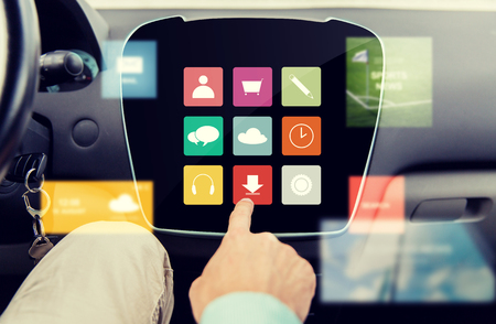 transport, driving, technology, media and people concept - close up of male hand with virtual applications icons on car computer screenの写真素材