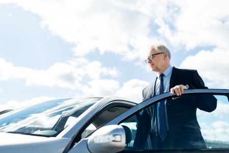 transport, business trip and people concept - senior businessman getting into carの写真素材