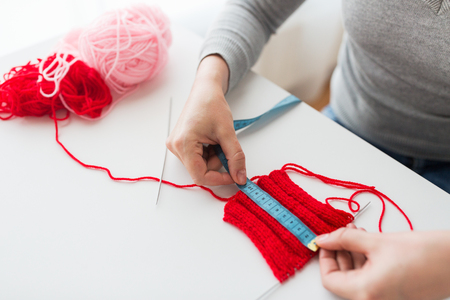 people and needlework concept - woman with measuring tape, knitting, needles and yarnの写真素材
