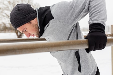 fitness, sport, exercising, training and people concept - young man doing triceps dip on parallel...