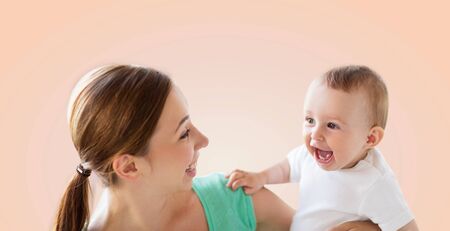 family, child and parenthood concept - happy smiling young mother with little baby over beige backgroundの写真素材