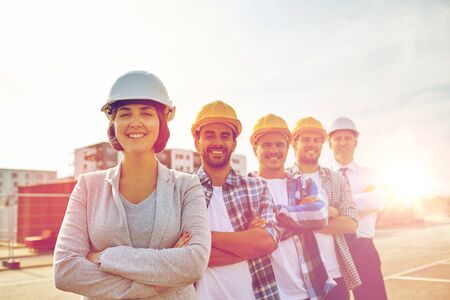 business, building, teamwork and people concept - group of smiling builders and architect in hardhats at construction siteの写真素材