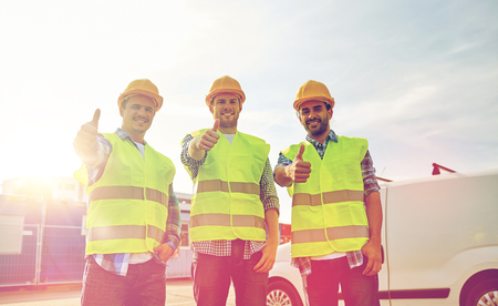 industry, building, construction and people concept - happy male builders in high visible vests...