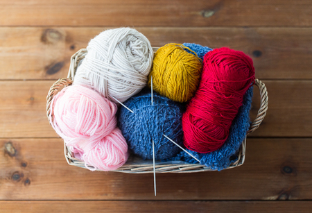 handicraft and needlework concept - wicker basket with knitting needles and balls of yarnの写真素材