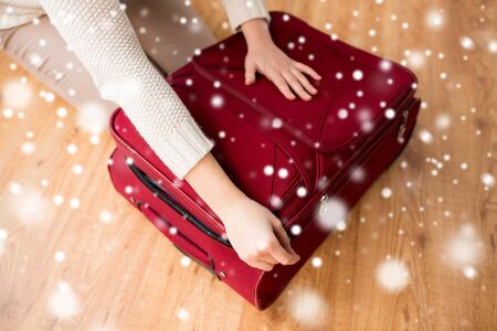 vacation, travel, tourism, winter holidays and objects concept - close up of woman packing and zipping bagの写真素材