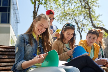education, high school and people concept - group of happy teenage students with notebooks learning at campus yardの写真素材