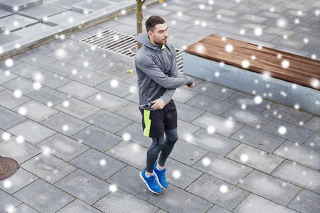 fitness, sport, people, exercising and healthy lifestyle concept - man skipping with jump rope outdoors over snowの写真素材