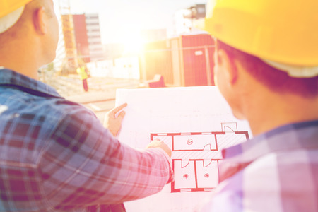 building, construction, development, teamwork and people concept - close up of builders with blueprint at building siteの写真素材