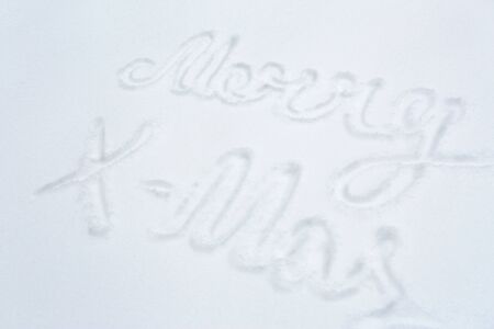 winter holidays and christmas concept - merry x-mas words on snow surfaceの写真素材