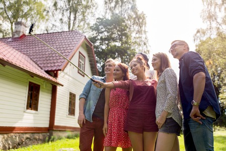 leisure, party, technology, people and holidays concept - happy friends taking picture with...