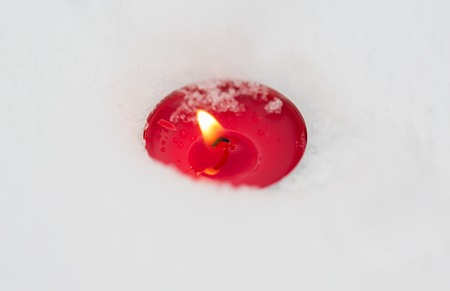 winter holidays and christmas concept - burning christmas candle on snowの写真素材