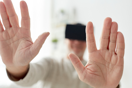 technology, augmented reality, gaming, entertainment and people concept - close up of senior man with virtual headset or 3d glasses playing videogame at homeの写真素材