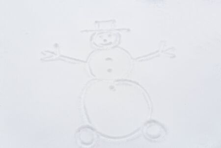 winter holidays and christmas concept - snowman drawing on snow surfaceの写真素材