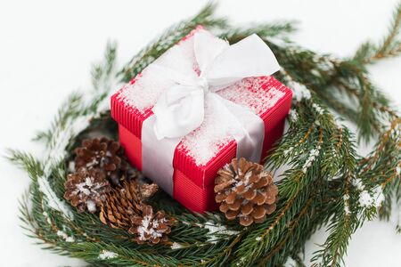christmas, winter holidays and greeting concept - gift box and fir wreath with cones on snow