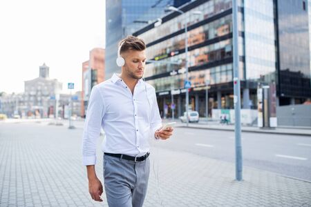 people, technology and lifestyle - happy young man with headphones and smartphone listening to music in cityの写真素材