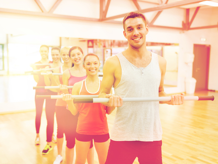 fitness, sport, training, gym and lifestyle concept - group of smiling people working out with barbells in the gymの写真素材