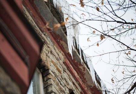 season, housing and winter concept - icicles hanging from building roofの写真素材