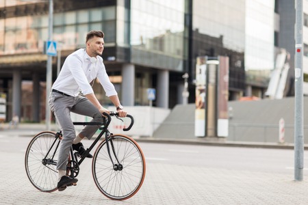 lifestyle, transport and people concept - young man with headphones riding bicycle on city streetの写真素材
