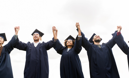 education, graduation and people concept - group of happy international students in mortar boards and bachelor gowns celebrating successの写真素材