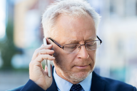 business, technology, communication and people concept - close up of senior businessman calling on smartphone in cityの写真素材
