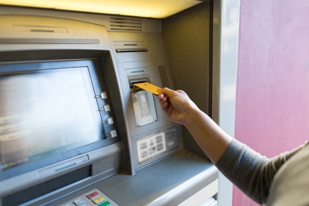finance, money, bank and people concept - close up of woman hand inserting card to atm machineの写真素材