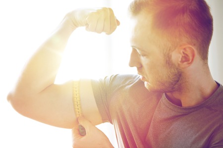 close up of male hands with tape measuring bicep