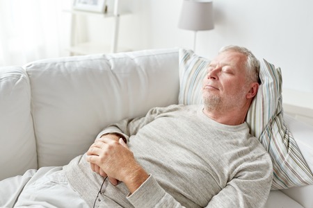 senior man sleeping on sofa at homeの写真素材