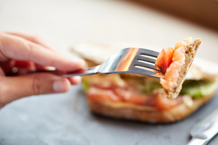 woman eating salmon panini sandwich at restaurant