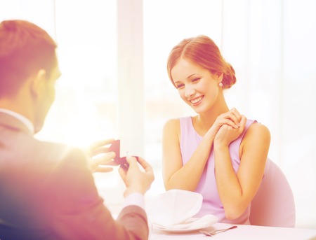 excited young woman looking at boyfriend with ring