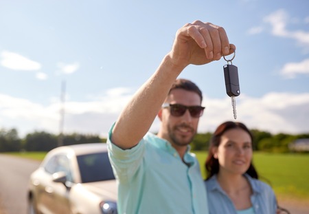 happy man and woman with car key outdoors