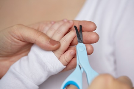 close up of hand with scissors trimming baby nailsの写真素材