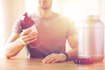 close up of man with protein shake bottle and jarの写真素材