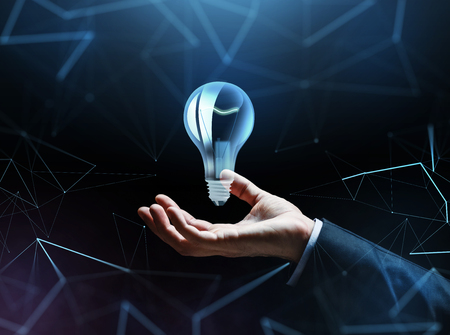businessman hand with bulb over dark backgroundの写真素材
